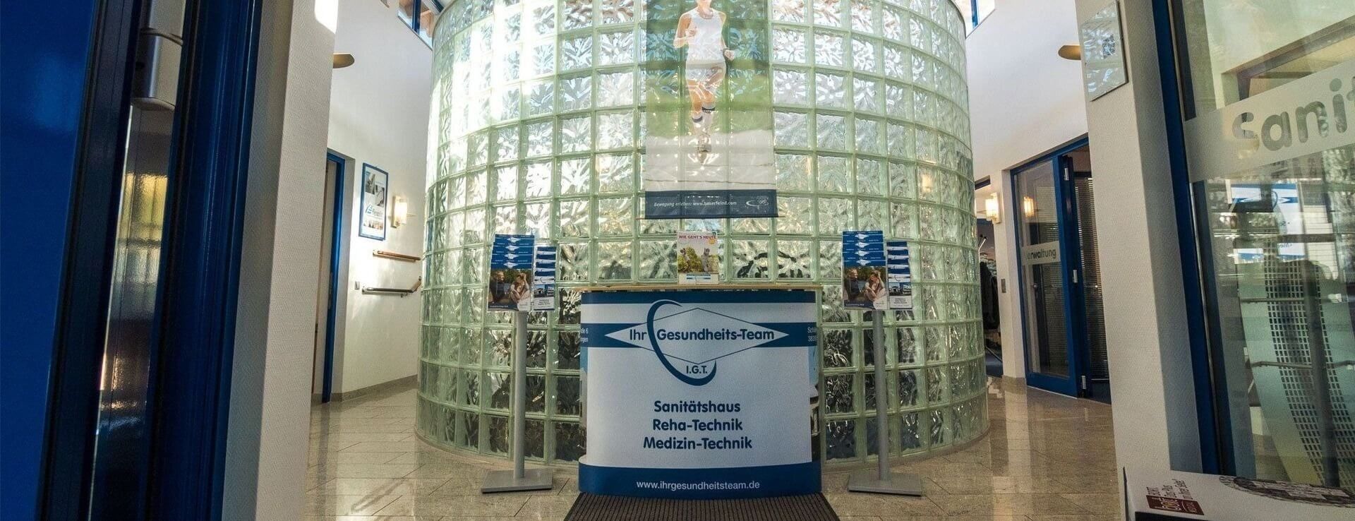 Eingangsbereich mit gläserner Wand aus Glasbausteinen und einem Tresen mit Informationsmaterial