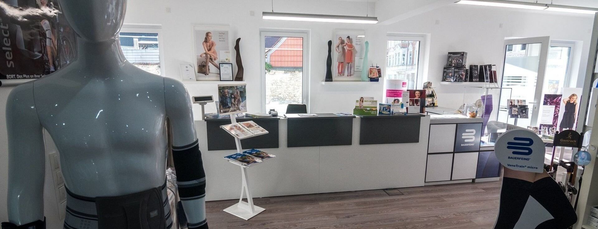 Innenraum eines modernen Ladengeschäfts mit Schaufensterpuppen, Verkaufstresen und Werbematerialien auf dem Boden und an der Wand